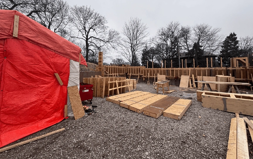 Construction site for Field Park with wooden framing and a red tarp covering materials. The ground is covered in gravel.