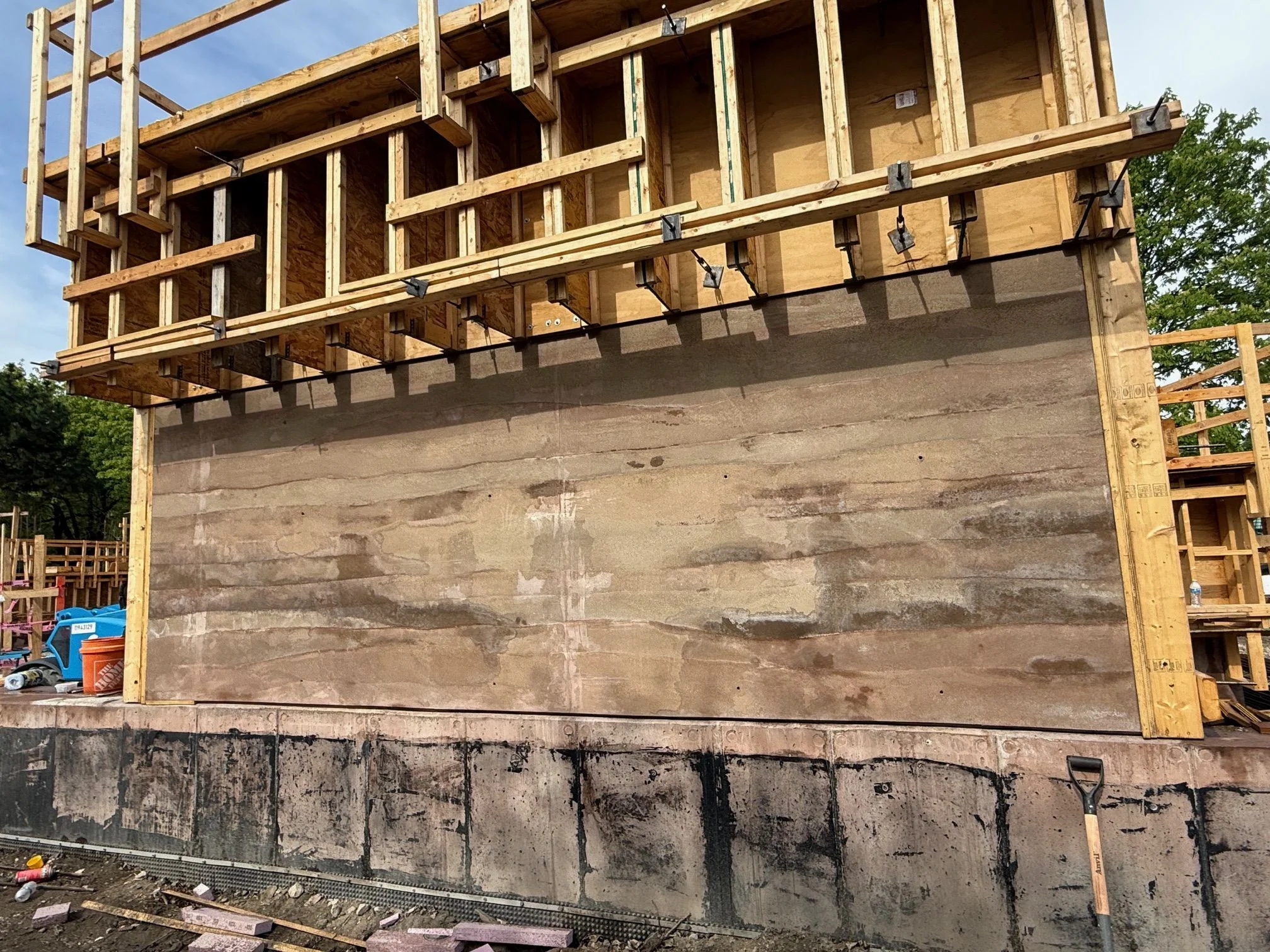 Construction of a rammed earth wall at Field Park, showing wooden formwork and the layered earth texture.