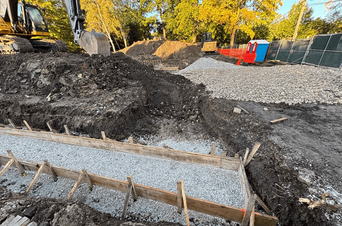 Construction site at Field Park with excavators, trenches, gravel, and portable restrooms.