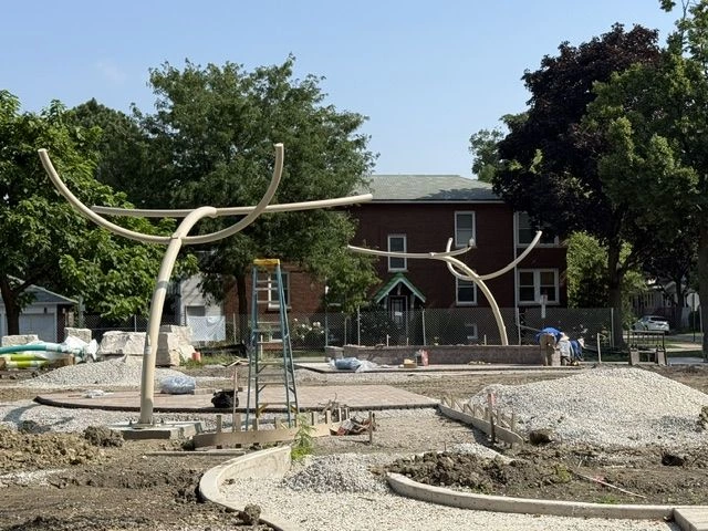 Construction of a splash pad at Longfellow Park, featuring abstract metal sculptures and landscaping in progress.