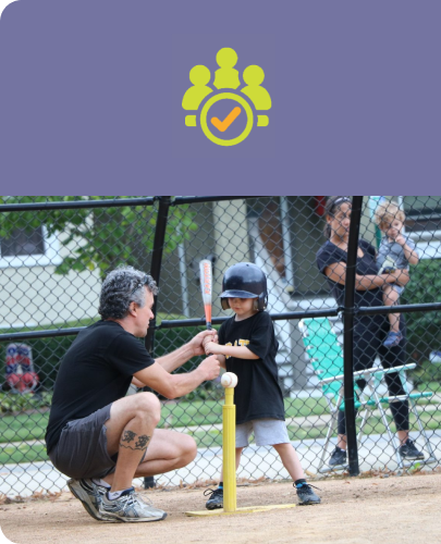 An adult coaching a child during a baseball practice