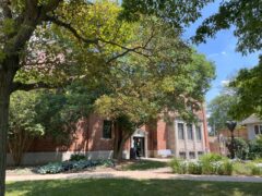The Dole Center exterior features red brick walls, large windows, and a welcoming entrance surrounded by lush greenery and