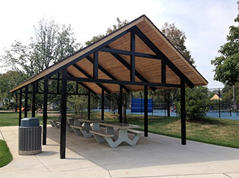 Taylor Park gazebo with picnic tables and benches, adjacent to a trash receptacle and park amenities.