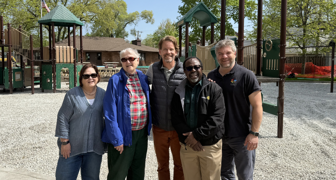 five board members pose in front of a park construction project