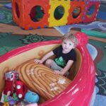 boy sits in large red canoe with toys