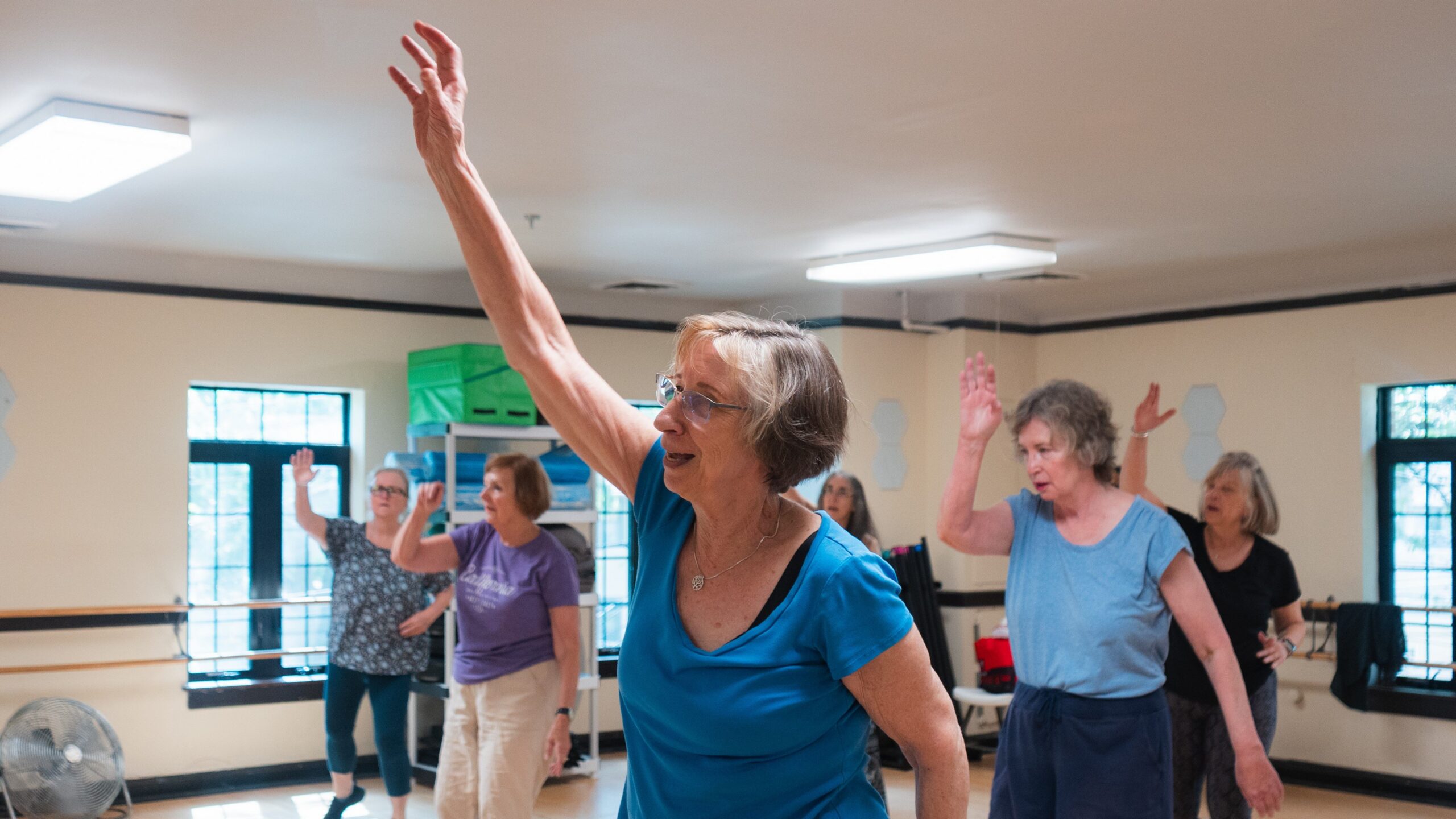 a group of women wave their hands in an exercise class