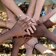 Diverse hands stacked together in a circle, symbolizing unity and teamwork for volunteer efforts.