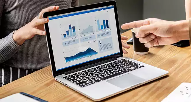 Business analytics dashboard displayed on a laptop during a team meeting.