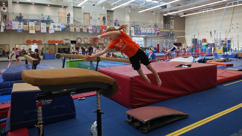 a male gymnast jumps onto the vault while twisting in the air