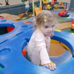 young child pops through a hole in a climbing structure