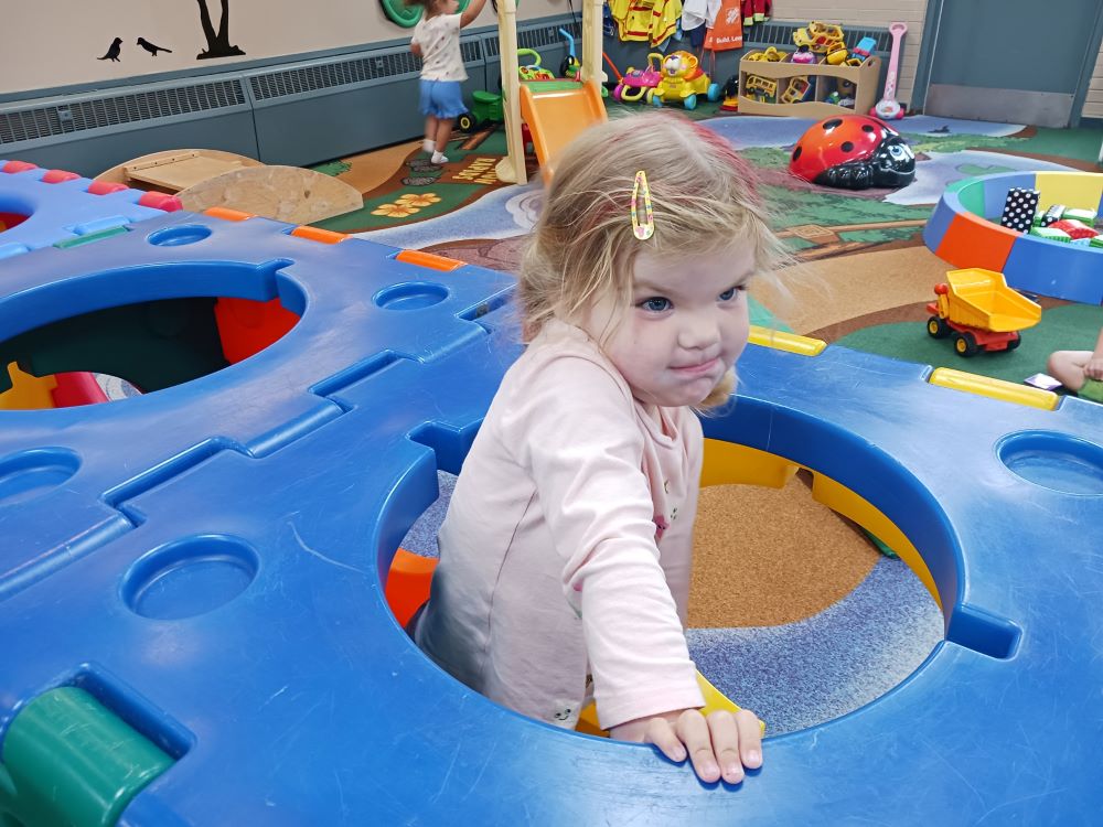 young child pops through a hole in a climbing structure