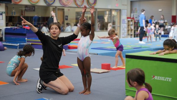 a coach holds up a gymnast's arms and points in the distance
