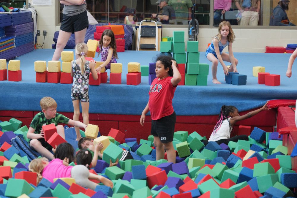 a group of kids play in a colorful foam pit