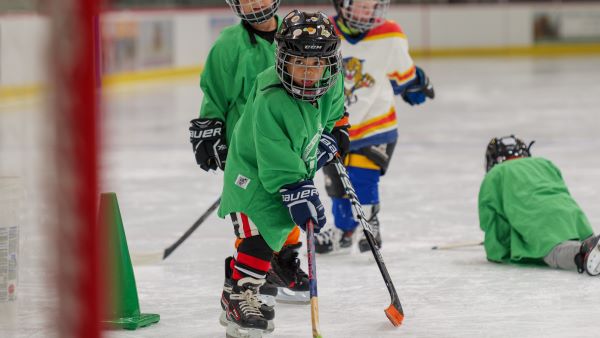 a young hockey player in a green jersey aims for the goal