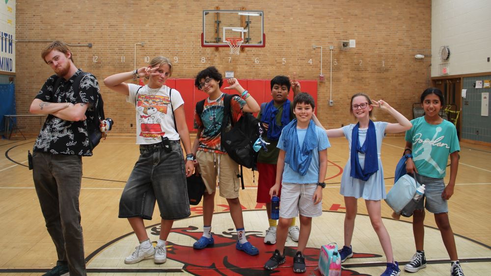 a group of campers and counselors pose in a gymnasium