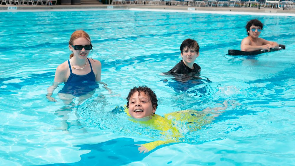 a boy swims across the pool and smiles