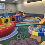 nature themed rug with tree decals on the walls, blocks, a ball pit, and slides