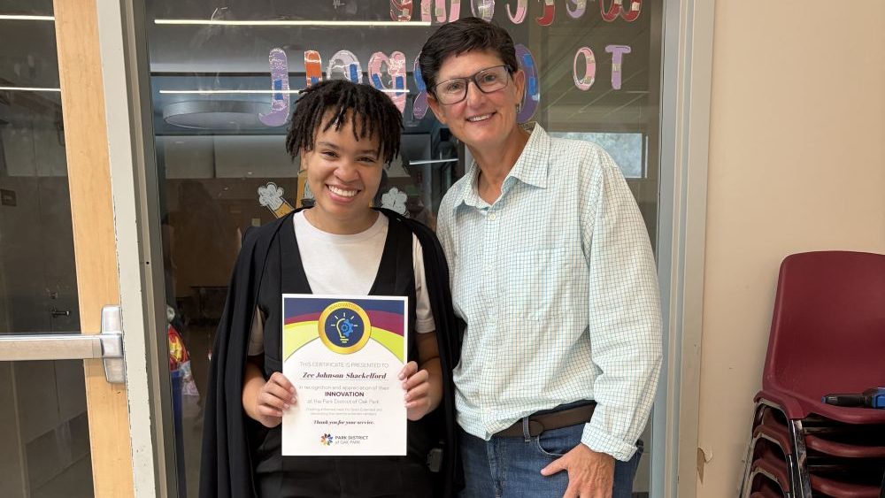 a seasonal staff holds their everyday values champion certificate and poses for a photo with the park district executive director