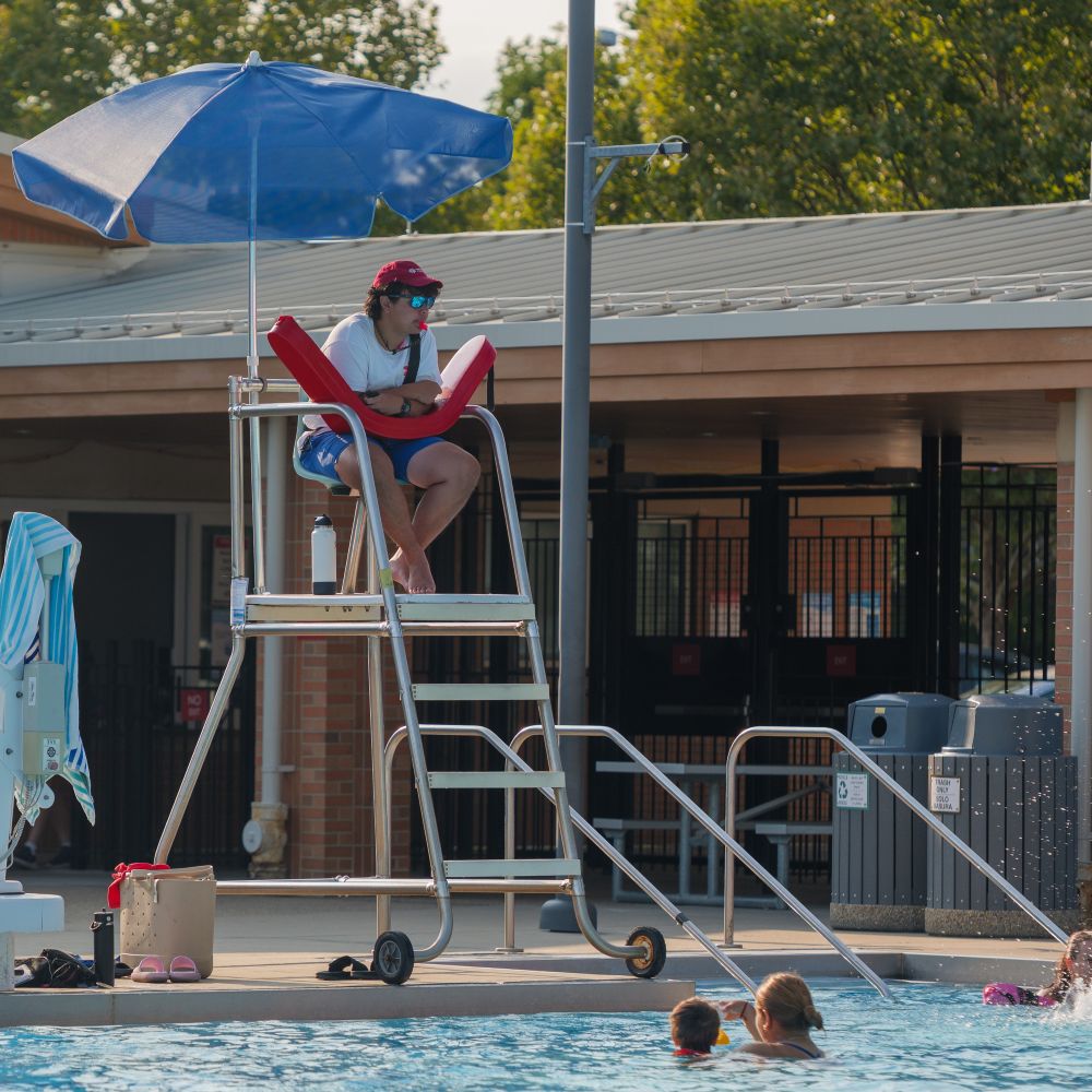 a lifeguard sits in his chair over the pool