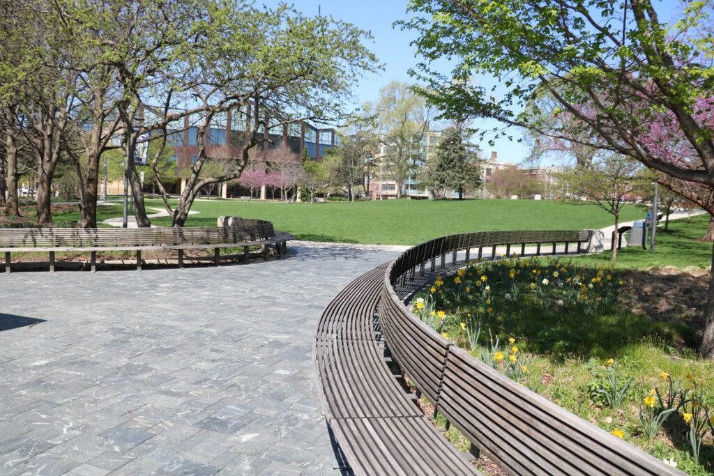 stone path leads into a large grassy park with long benches
